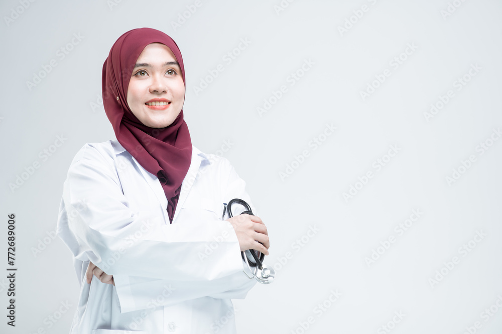 Happy beautiful asian Muslim woman doctor in medical coat standing with crossed arms, and with a smiley face ready to serve, on white background. Happy beautiful asian Muslim woman doctor in medical coat standing with crossed arms, and with a smiley face ready to serve, on white background.