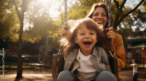 Happy boy with mother having fun swinging on playground. Happy family concept.