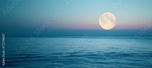 Full moon over blue sea water in pastel sky, evening natural background