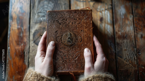 A pair of hands holding a locked leather journal its pages filled with cryptic symbols and clues to an unsolved mystery. . . photo