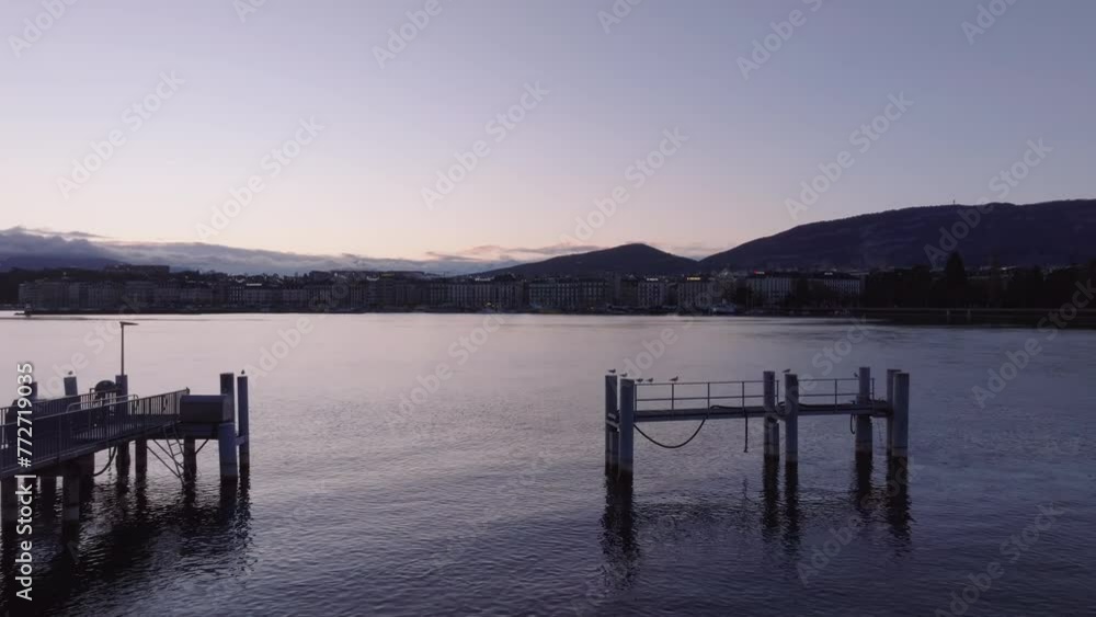 Forwards fly above pier in lake. Lightly rippled water surface reflecting twilight sky. Geneva, Switzerland Forwards fly above pier in lake. Lightly rippled water surface reflecting twilight sky. Geneva, Switzerland