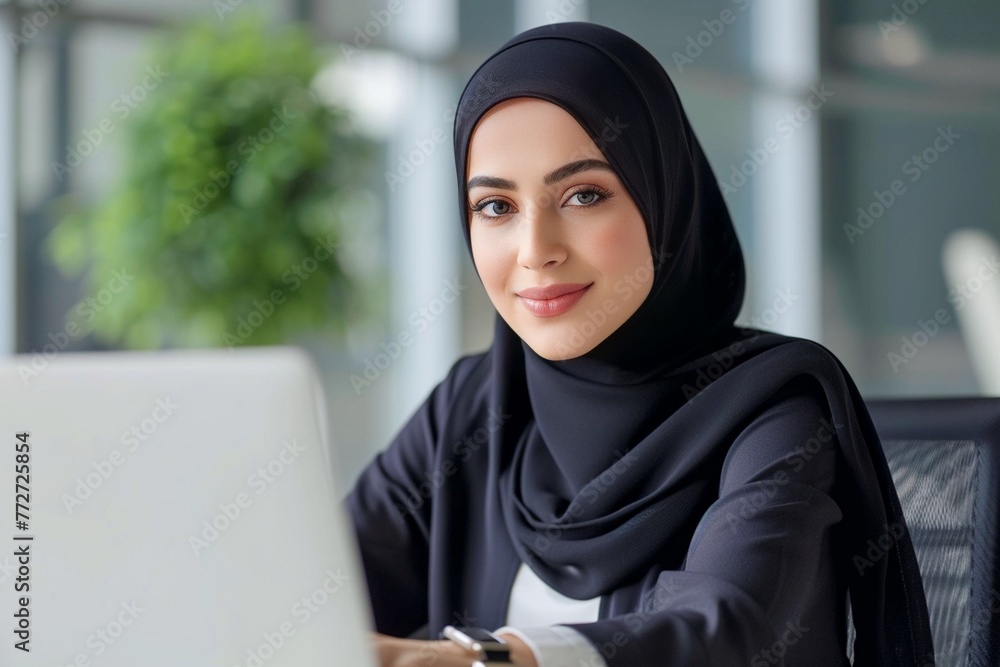 Muslim woman wearing a hijab is working on a laptop in the office Muslim woman wearing a hijab is working on a laptop in the office