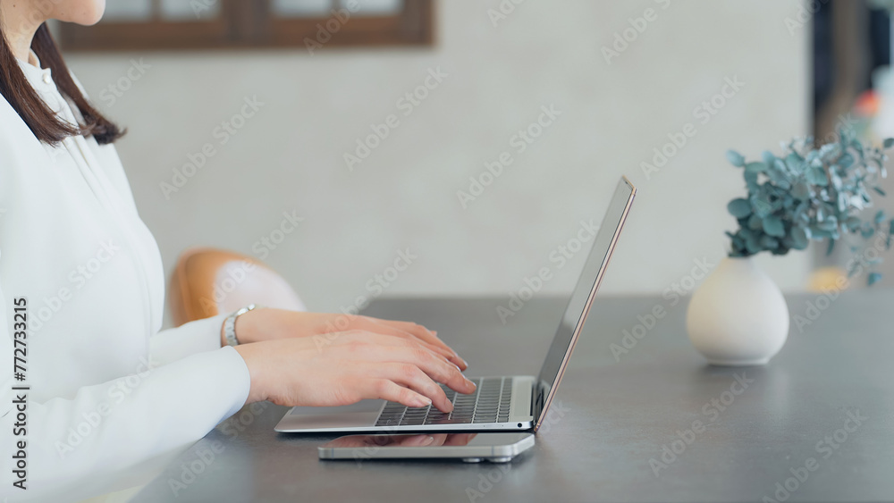 Naklejka premium A woman using a laptop and smartphone indoors