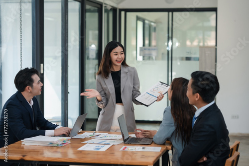 Businesswoman presenting graph chart to colleagues in a meeting. Professional corporate team discussion in modern office. Corporate business and teamwork concept.