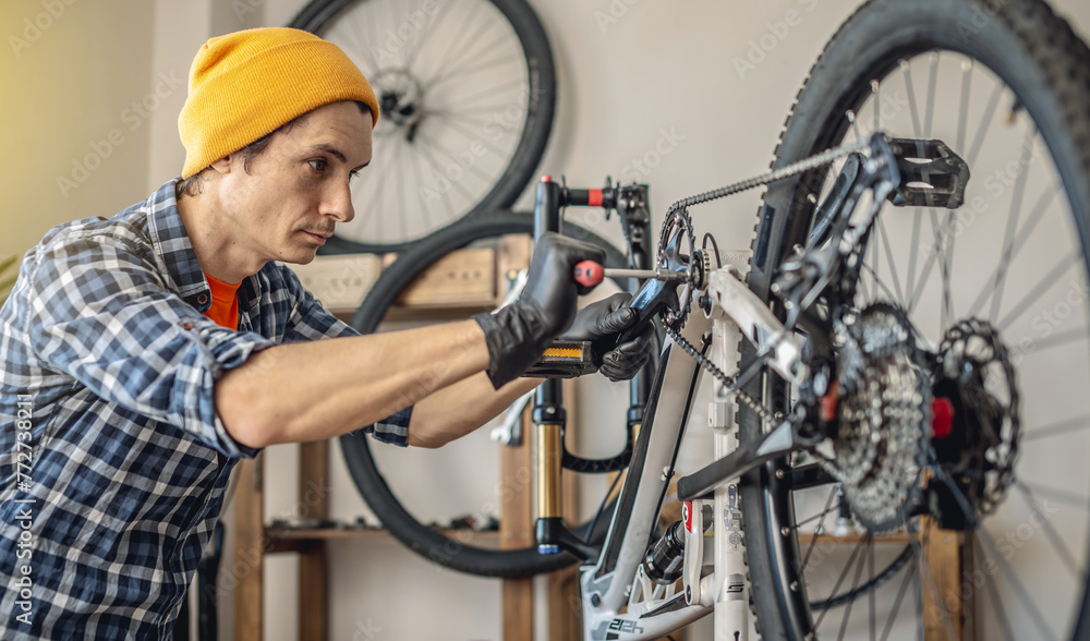 A male bicycle mechanic repairs a mountain bike in a workshop. The concept of preparation for the new season, repair and maintenance A male bicycle mechanic repairs a mountain bike in a workshop. The concept of preparation for the new season, repair and maintenance