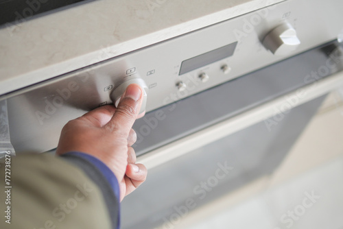  man hand setting temperature control on oven.