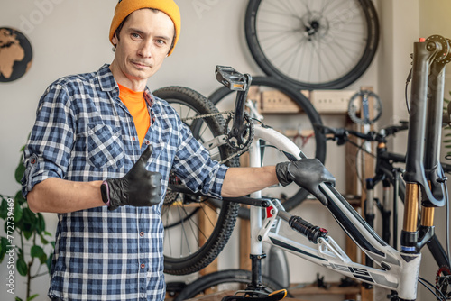 A male bicycle mechanic in the workshop disassembles a mountain bike and repairs it. Maintenance concept, preparation for the new season