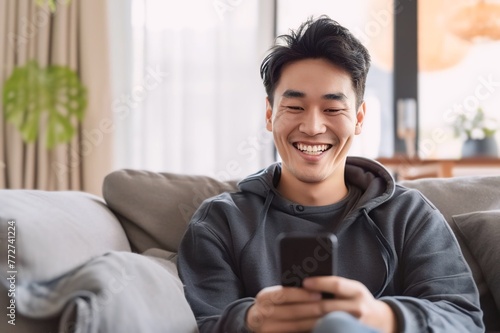 Asian man playing with smartphone while laughing