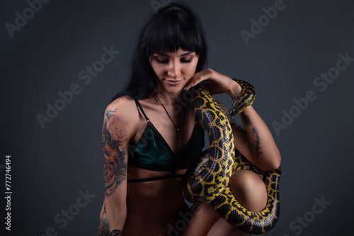 Photo of the young brunette woman sitting with yellow anaconda