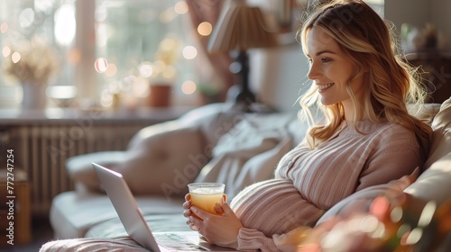 Pregnant Woman Sits on a Sofa and Drinks Tea. Laptop on the Sofa. Good Daylight