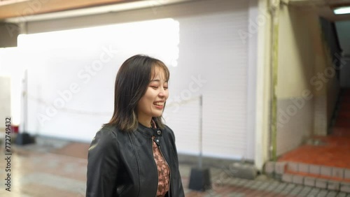 Slow-motion video of an Okinawan woman in her 20s in winter clothes walking on Kokusai Street in Naha City, Okinawa Prefecture with a smile 沖縄県那覇市の国際通りを笑顔で歩く冬服の20代の沖縄県民女性のスローモーション映像 photo