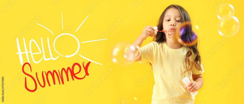 Fototapeta premium Cute little girl blowing soap bubbles on yellow background