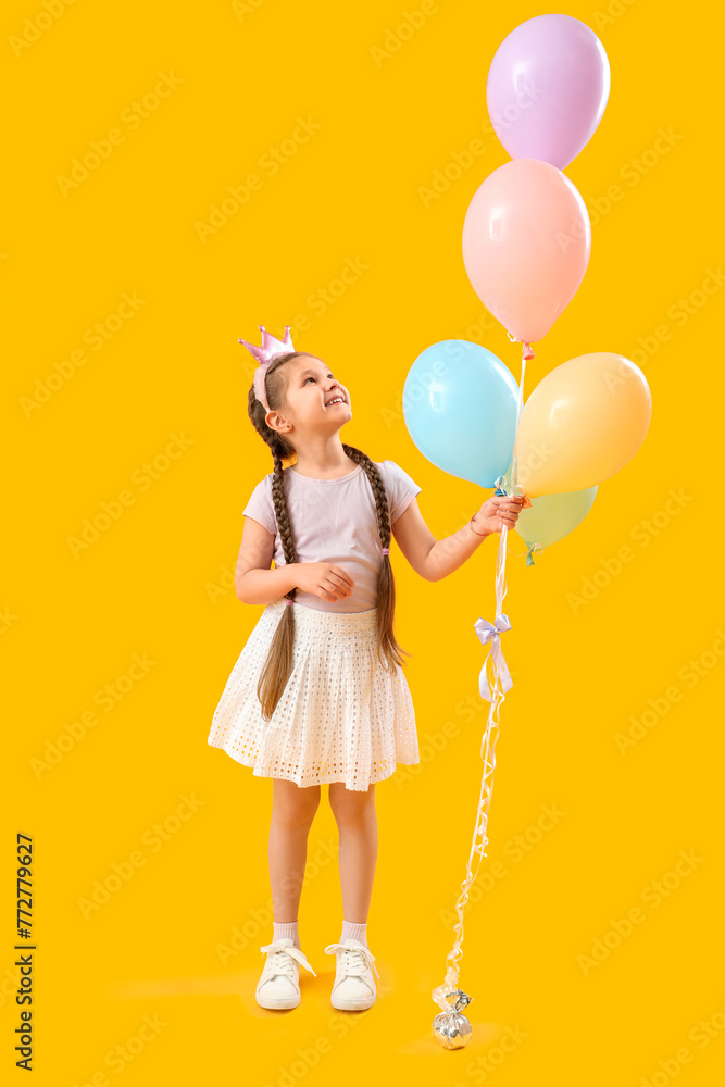 Little girl in crown with balloons on yellow background. Children's Day celebration