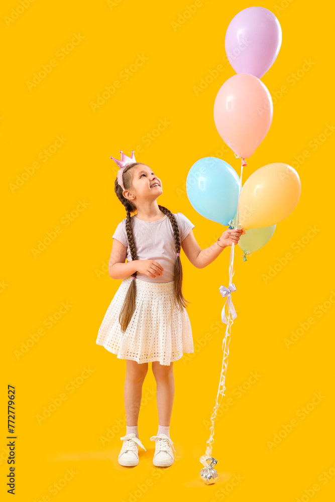 Little girl in crown with balloons on yellow background. Children's Day celebration Little girl in crown with balloons on yellow background. Children's Day celebration
