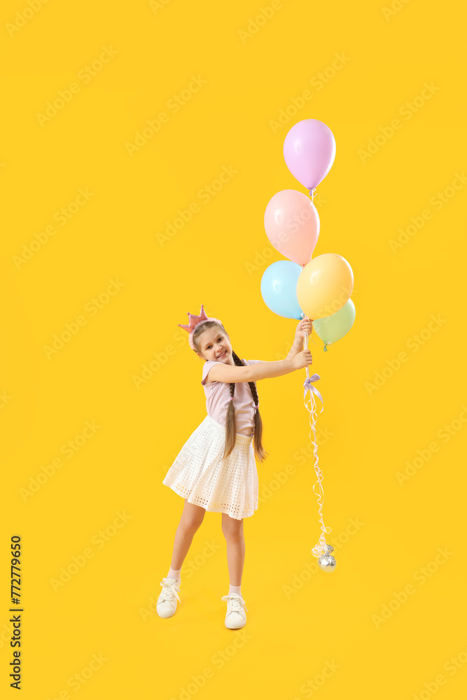 Little girl in crown with balloons on yellow background. Children's Day celebration Little girl in crown with balloons on yellow background. Children's Day celebration