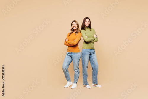 Full body young friends two women they wear orange green shirt casual clothes together hold hands crossed folded look camera isolated on plain pastel light beige background studio. Lifestyle concept.