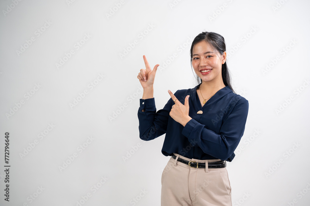 Attractive Asian woman is pointing her index fingers up to an empty space, white studio background. Attractive Asian woman is pointing her index fingers up to an empty space, white studio background.