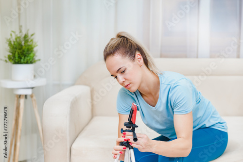 Fitness woman blogger preparing to recording video on smartphone about training at home, Online fitness class at home: A girl utilizes the sofa for a workout session in her room