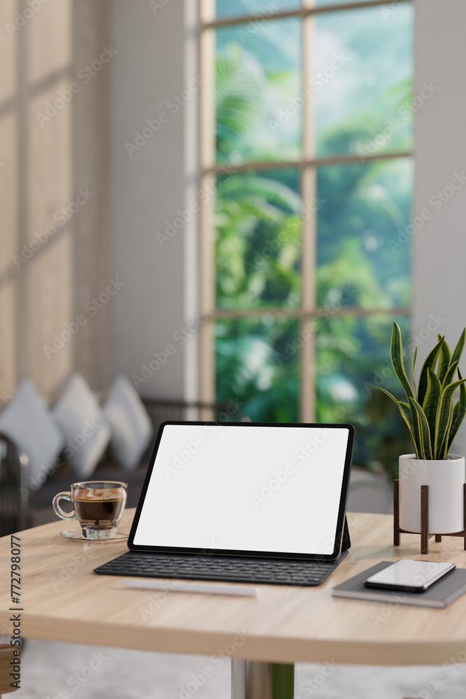 A white-screen digital tablet and accessories on a wooden table in a contemporary living room. A white-screen digital tablet and accessories on a wooden table in a contemporary living room.