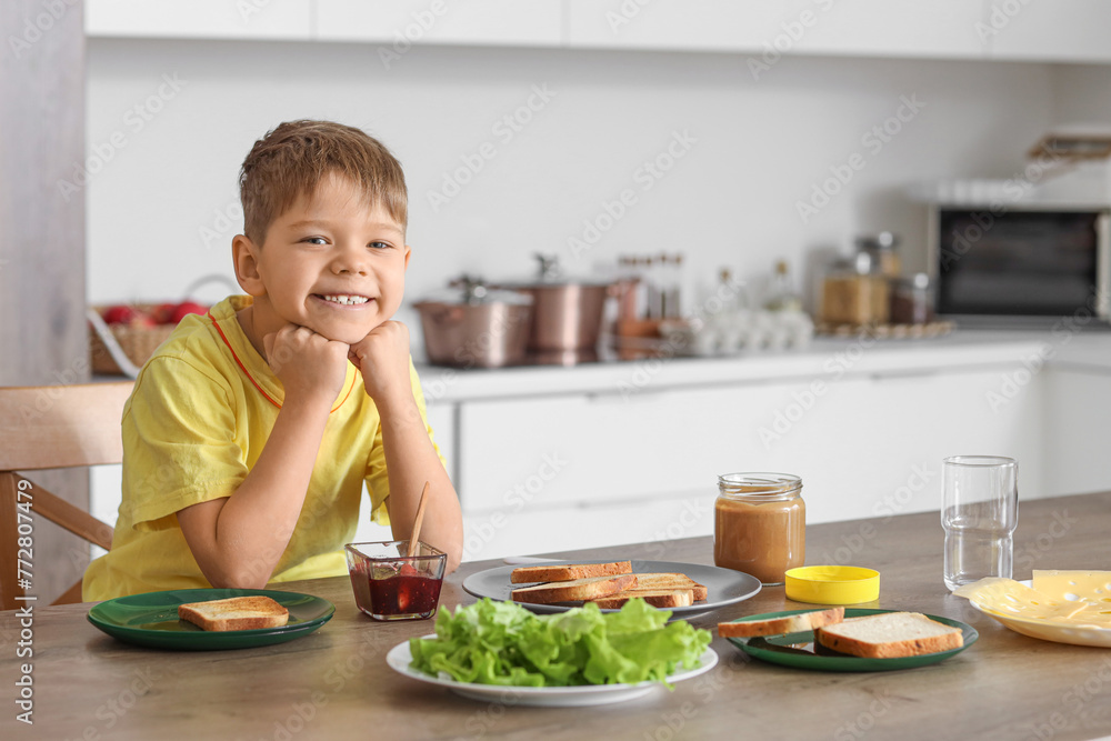 Cute little boy making toasts at table in kitchen Cute little boy making toasts at table in kitchen