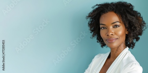 
Image of a successful African American businesswoman in her early 40s, posing elegantly on a pale blue background, smiling brightly at the camera copy space