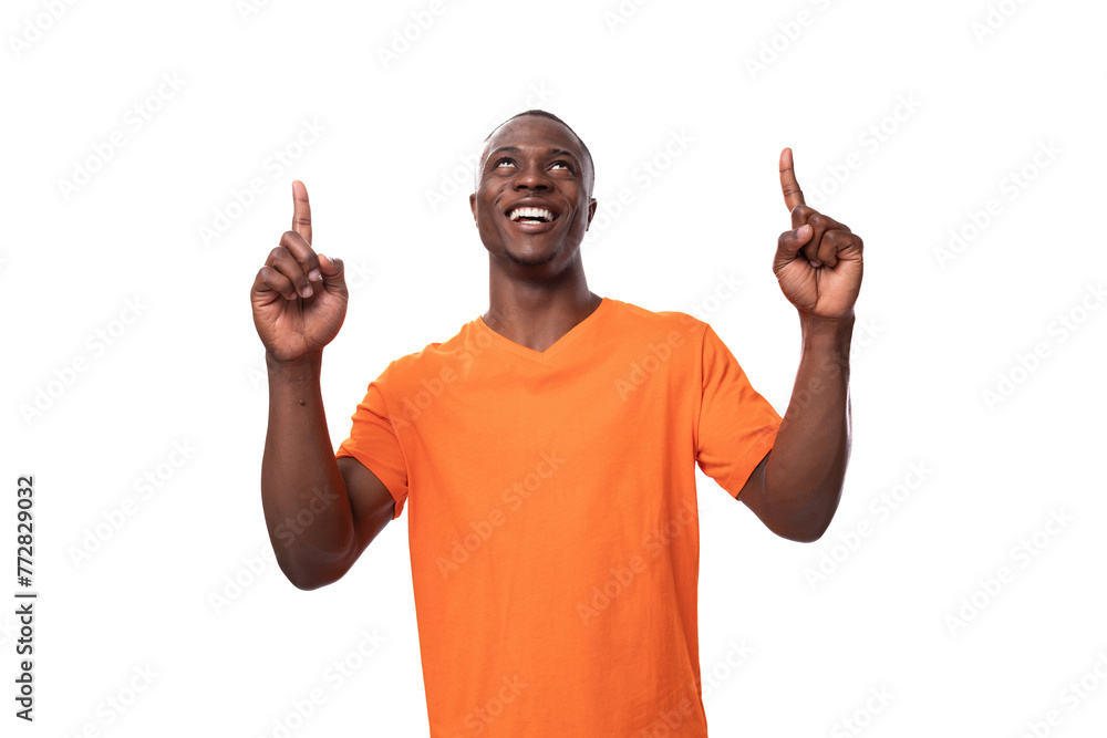 young african guy dressed in an orange t-shirt points with fingers on a white background with copy space young african guy dressed in an orange t-shirt points with fingers on a white background with copy space