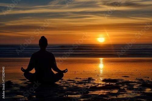 silhouetted figure meditating on beach at sunset © Natalia