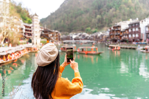 Young female tourist taking a photo of the Feng Huang Ancient Town, The famous tourist destination at Hunan Province, China