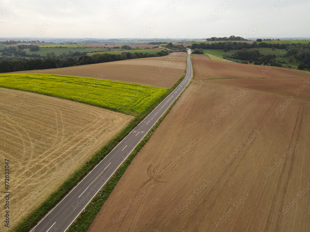 Aerial view of a long road between country fields in the countryside