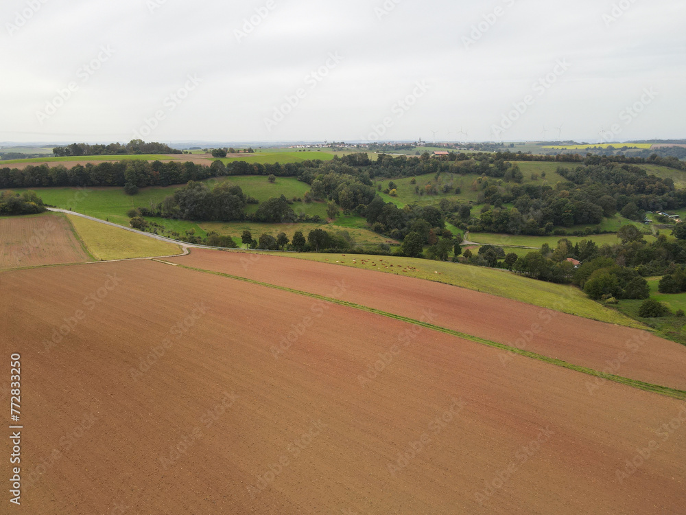Aerial view of country fields with plowed soil and trees in the countryside 