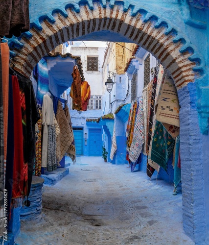 arched doorway with colourful carpets on the wall in the historic blue city of Chefchaouen in northern Morocco