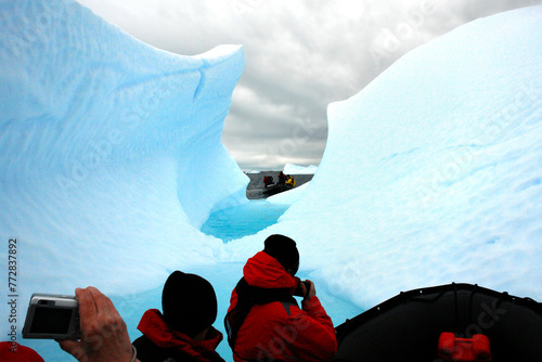 Tourists in Antarctica on a pontoon admiring an iceberg photo