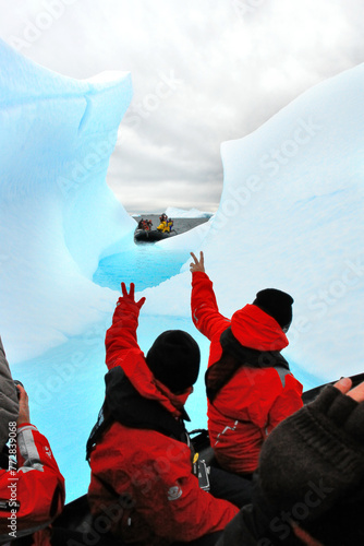 Tourists in Antarctica on a pontoon admiring an iceberg © robnaw