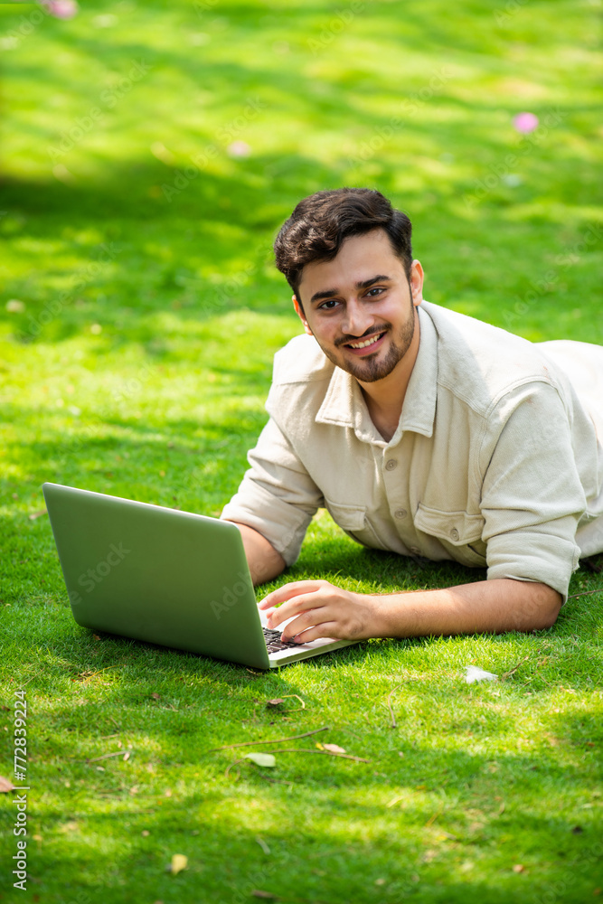 Indian man sitting on glass and using computer Indian man sitting on glass and using computer