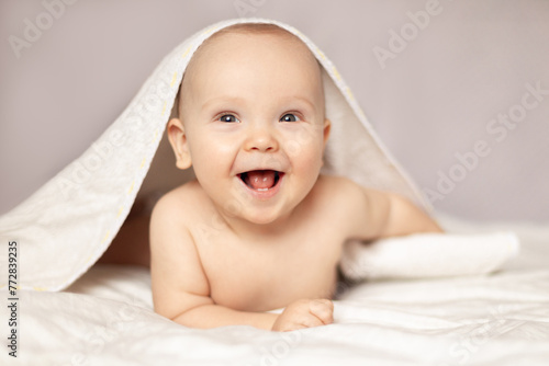 baby laughing in bed after bath or shower, Adorable happy baby in towel © Leka
