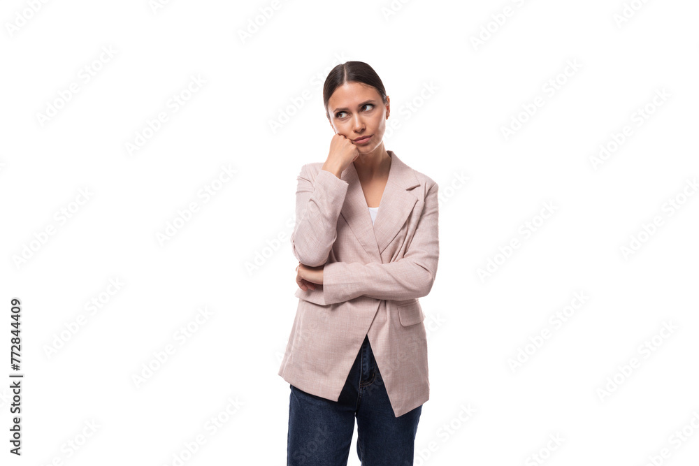 young smart caucasian woman with a ponytail hairstyle dressed in a jacket and jeans stands thoughtfully on a white background young smart caucasian woman with a ponytail hairstyle dressed in a jacket and jeans stands thoughtfully on a white background