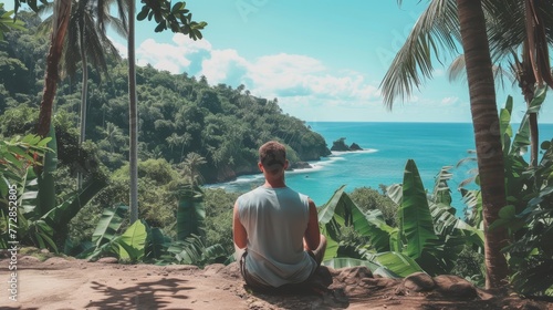 Serene image of a man sitting in meditation overlooking a tranquil blue sea surrounded by tropical foliage.