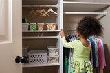 child organizing a closet with new hangers and bins