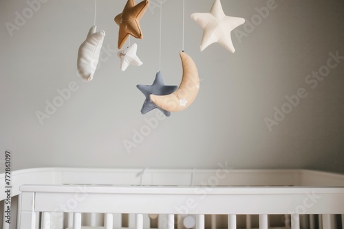 star and moon mobile spinning above a white crib © studioworkstock