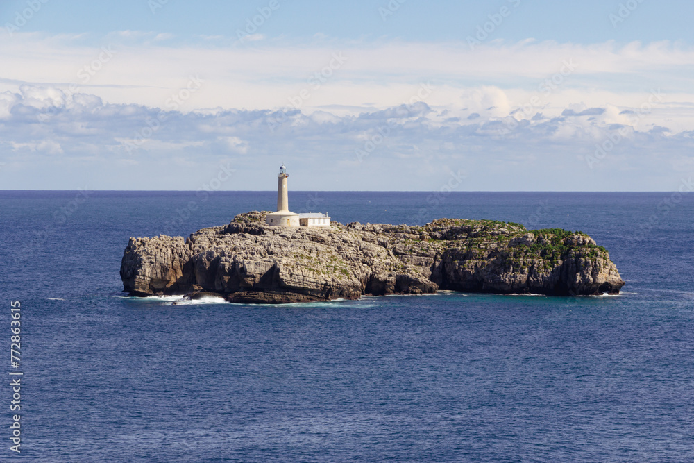 Seascape with lighthouse on top of a rocky island.