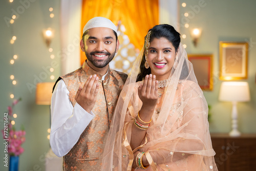 Happy indian muslim couple wishing for ramadan festival by saying with hand gesture by looking at camera - concept of islamic festival, togetherness and festive greeting.