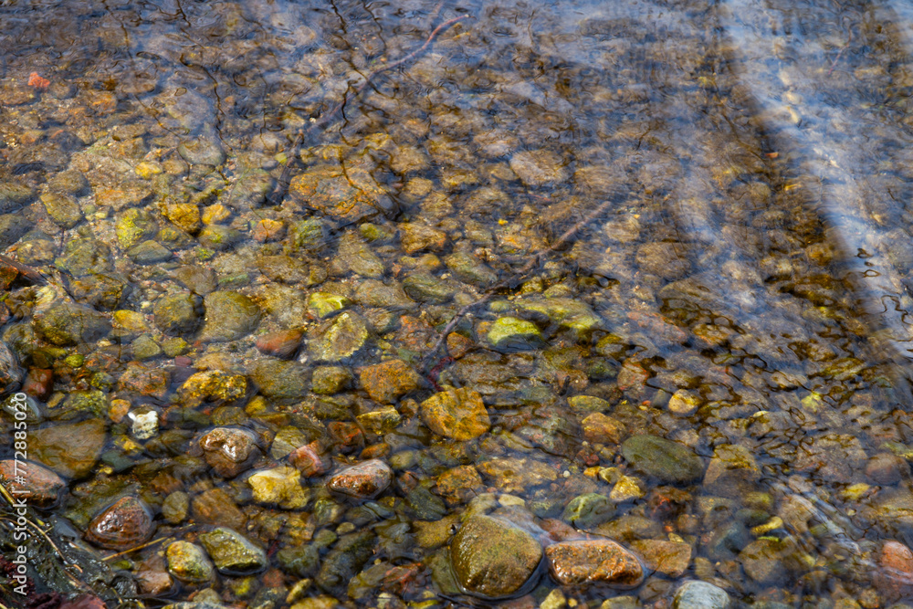 Texture, background. The surface of the water in the river with pebbles