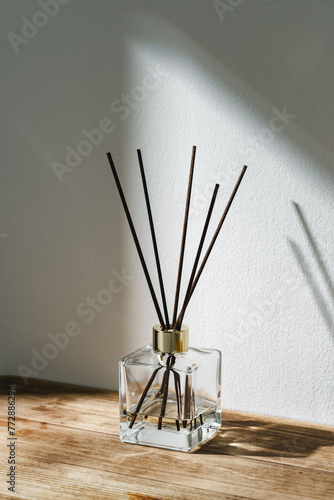 Sunlit Diffuser Bottle With Reeds Casting Shadows on a White Wall