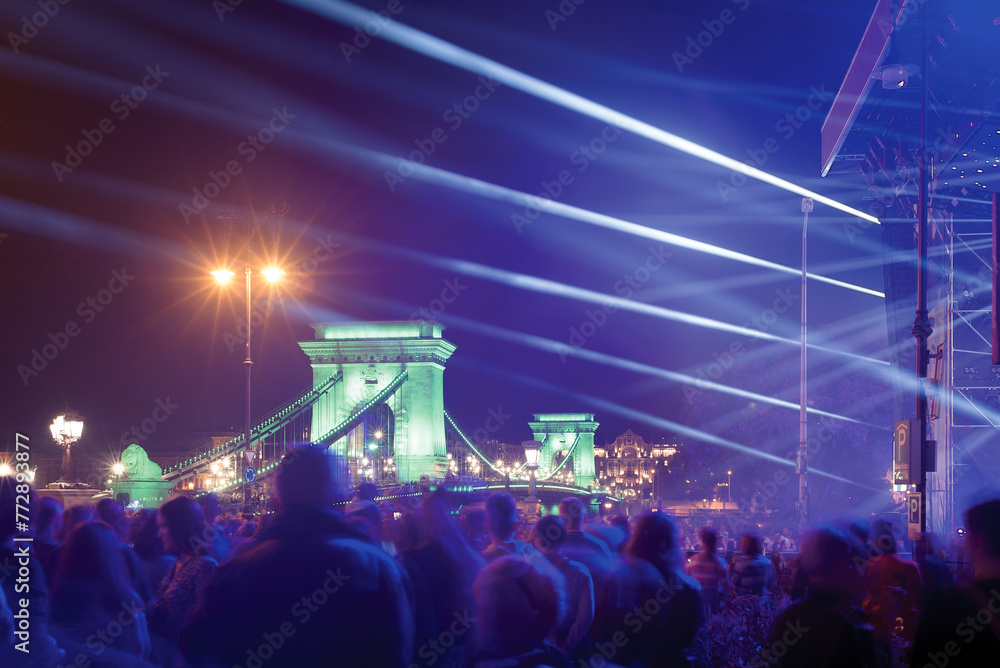 Fototapeta premium Night open air concert, light rays against Chain Bridge