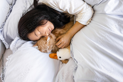 Young Asian woman with cute cat sleeping in bed