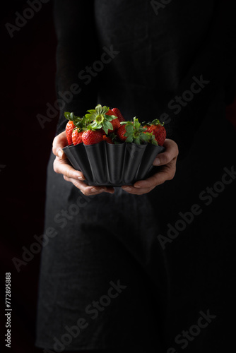 Delicious, ripe, red strawberries in a metallic bowl against a black background