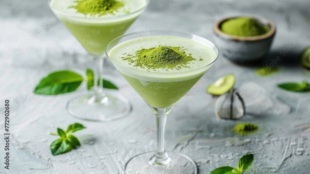 Matcha cocktails in martini glasses with green matcha powder on top.