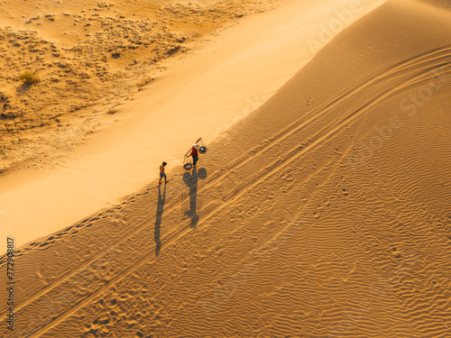 Aerial view of a peasant woman carries a bamboo frame on the shoulder across sand dunes in Ninh Thuan province, Vietnam. It is one of the most beautiful places in Vietnam