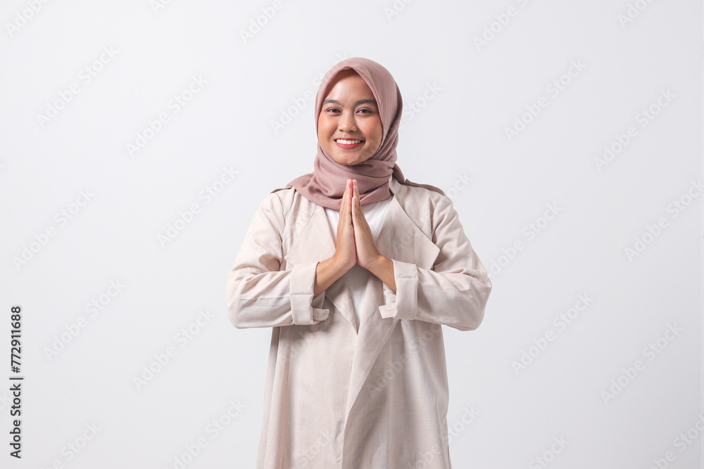 Portrait of excited Asian hijab woman in casual suit showing apologize and welcome hand gesture. Businesswoman concept. Isolated image on white background