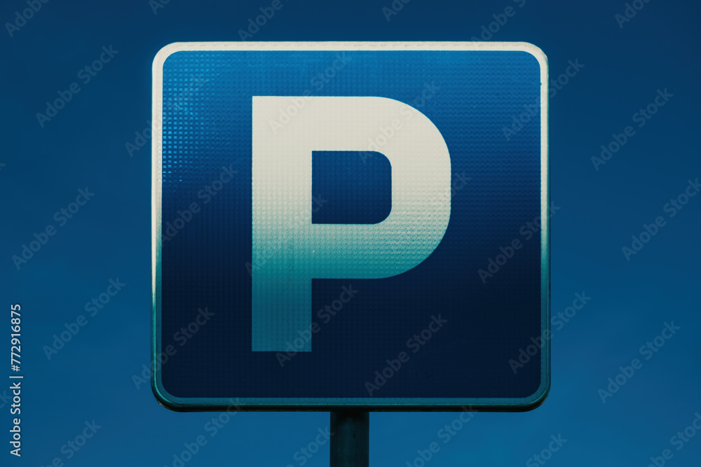 Parking area blue sign with white letter P illuminated by the warm sunset light Parking area blue sign with white letter P illuminated by the warm sunset light
